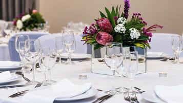 A dining table set with multiple wine glasses, plates, and cutlery, with a centerpiece of flowers and candles.