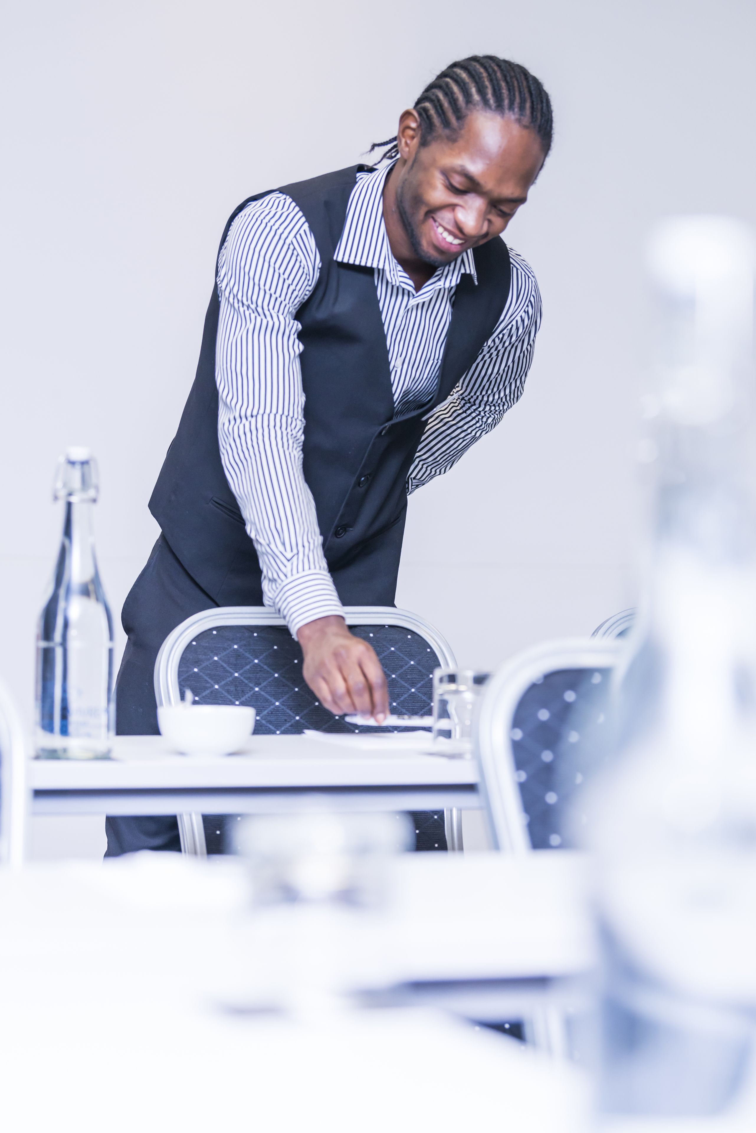 Una persona preparando una mesa de comedor con una botella de agua y un tazón.