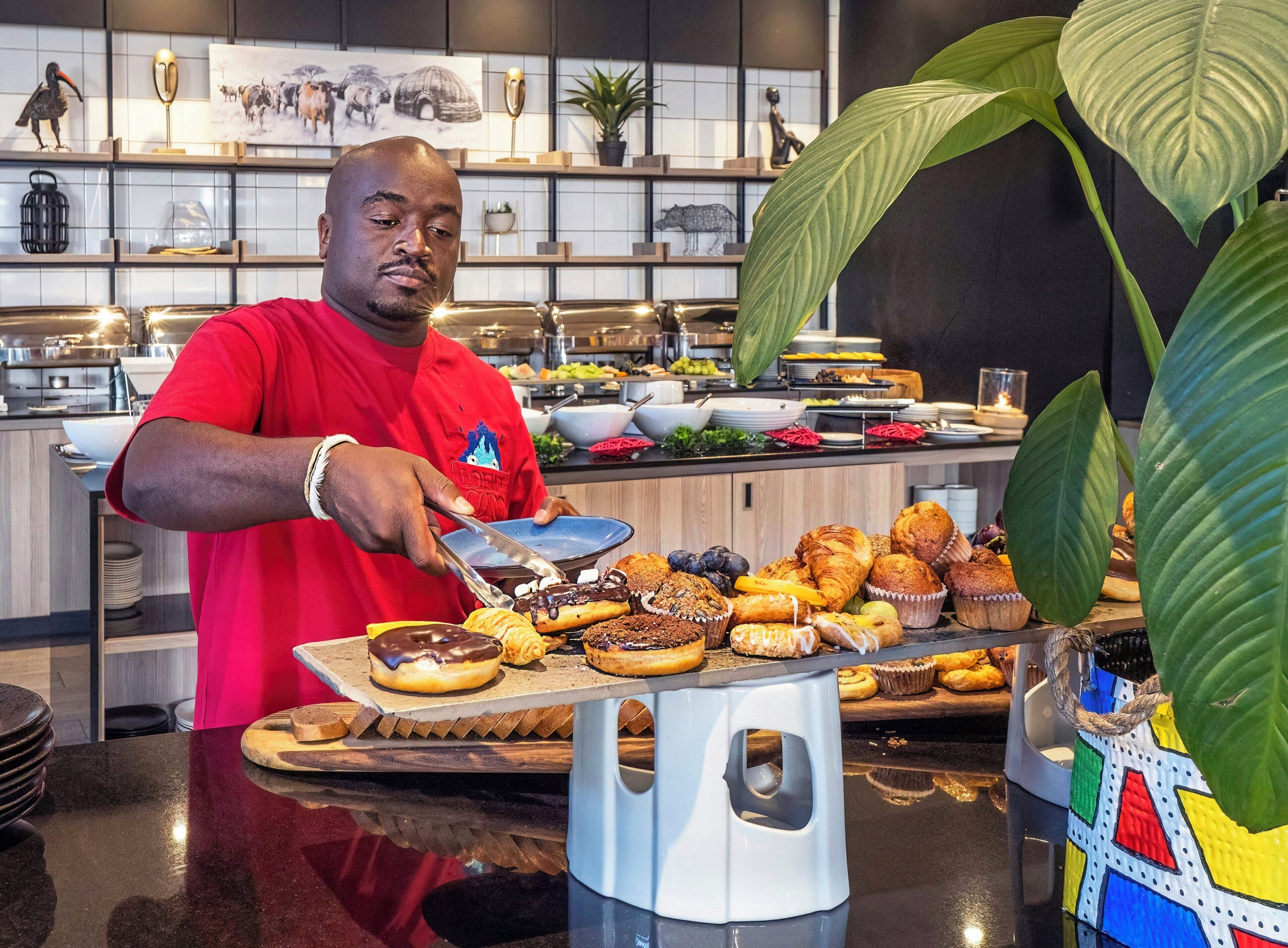 Een buffetopstelling met diverse gerechten en een persoon die bedient.
