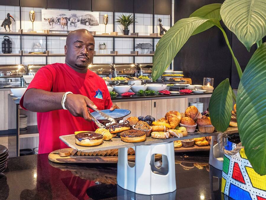 Montaje tipo bufé con diferentes alimentos y una persona sirviendo.
