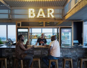 A bar with a 'BAR' sign, a bartender, and two customers seated at the bar.