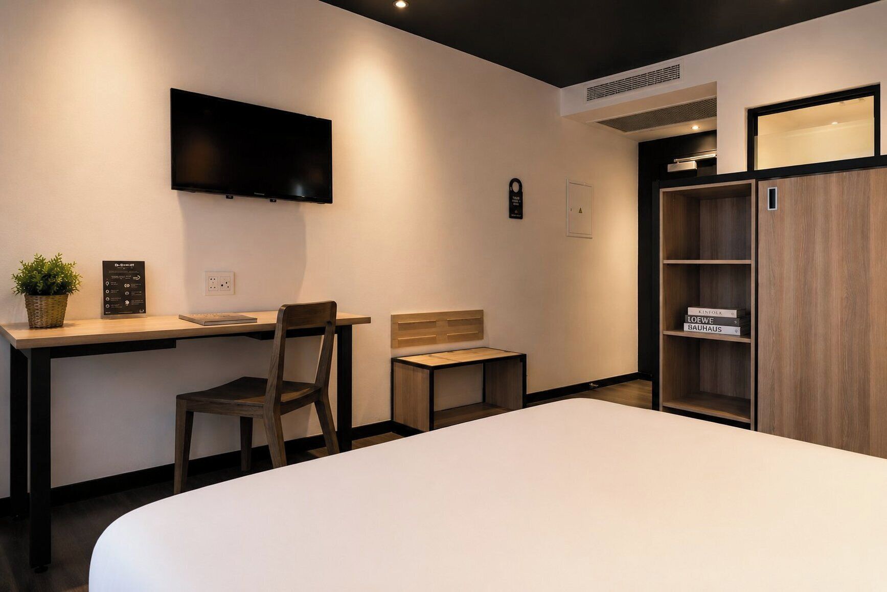 Une chambre d’hôtel équipée d’un lit, d’un bureau, d’une chaise, d’une télévision et d’une armoire.