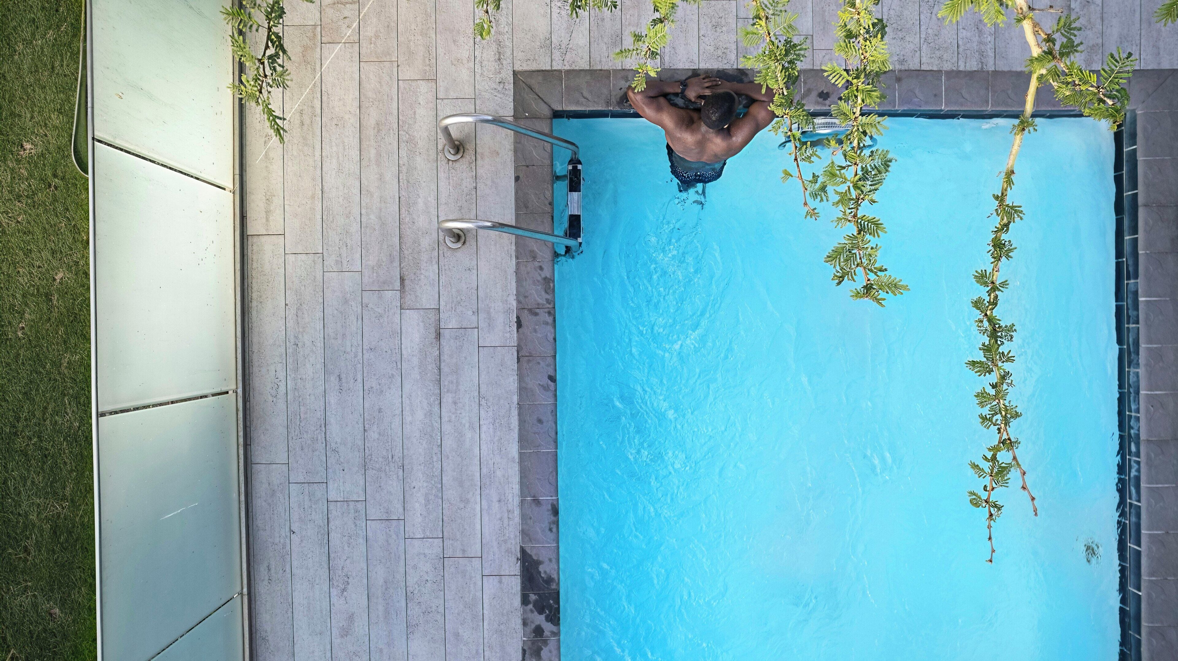 A swimming pool with a metal ladder and a tiled deck.