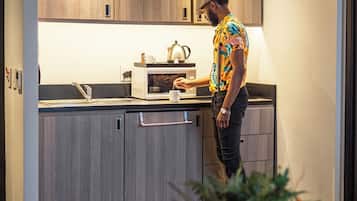 A modern kitchen with wooden cabinets, a microwave, and a kettle.
