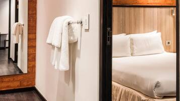 Habitación de hotel con cama, un cabecero de madera y un espejo que refleja el espacio.