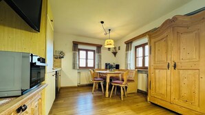 Eine Küche mit Holzausstattung, einer eingebauten Mikrowelle, einem Esstisch mit vier Stühlen und einem großen Holzschrank.