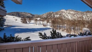 Eine verschneite Landschaft mit einer Holzterrasse und blauem Himmel.