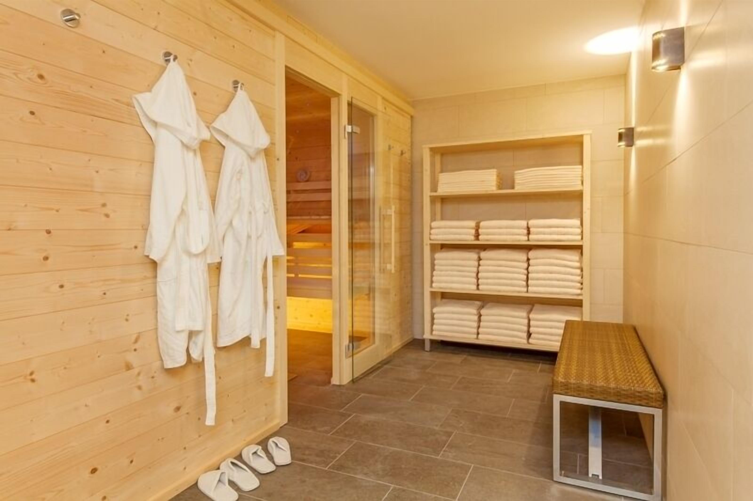 A wooden interior with a sauna, towels on shelves, and a bench.
