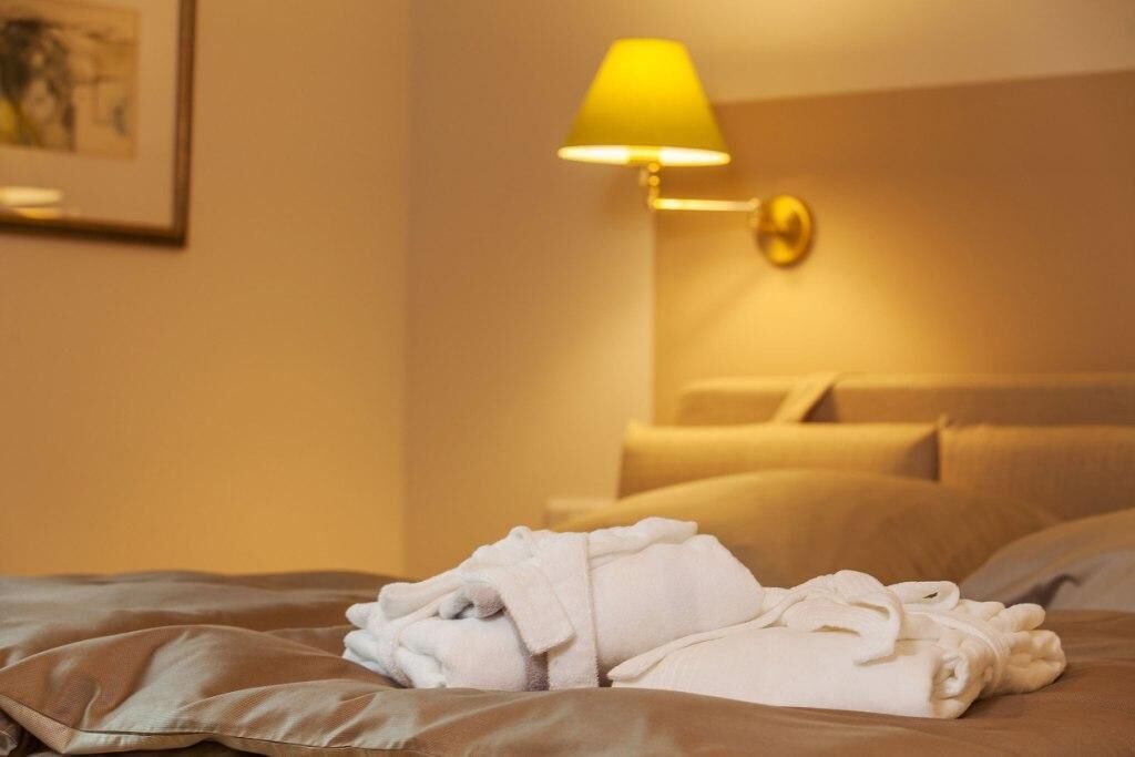A hotel room with a bed, a lamp, and a framed picture on the wall.