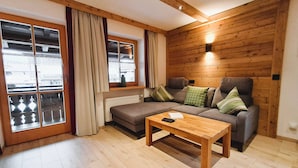 Una sala de estar acogedora con un sofá, una mesa de centro de madera y una ventana con cortinas.