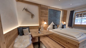 Una habitación acogedora con un banco de madera, una mesita con velas y una cama con almohadas.