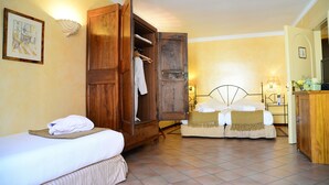 Habitación de hotel con dos camas, un armario de madera, una mesita de noche y un escritorio pequeño con una lámpara.