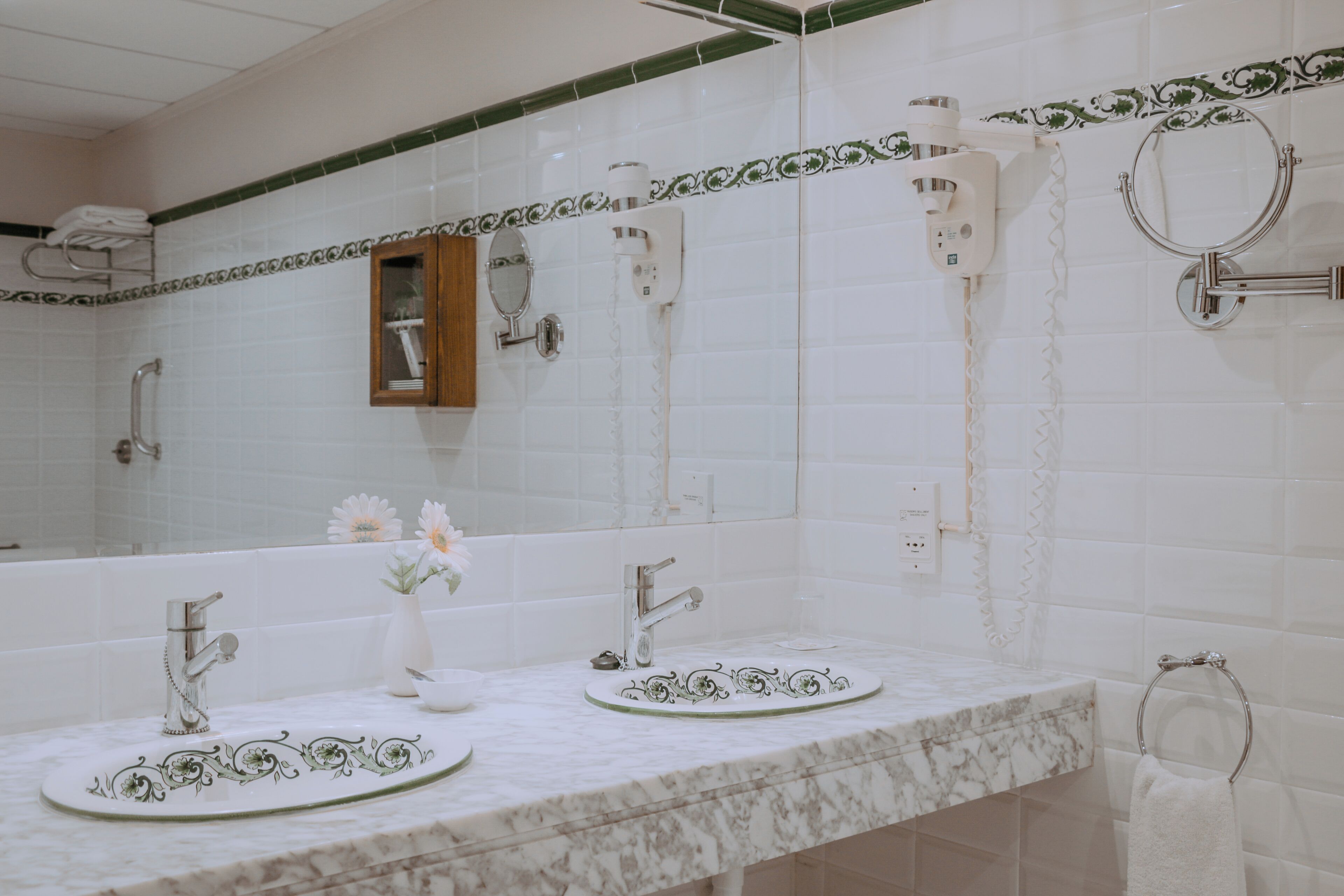 Un baño con dos lavamanos, un espejo, un toallero y una ducha.