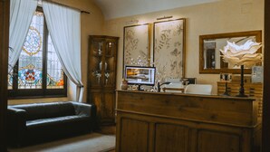 Una sala de estar acogedora con un aparador de madera, un televisor y un espejo con motivos florales.