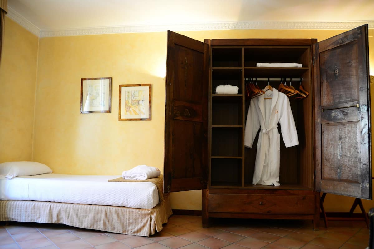 Ein Schlafzimmer mit einem Bett, einem Holzschrank und einem gerahmten Bild an der Wand.