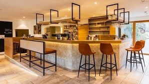 A modern bar area with a counter, stools, and shelves stocked with glasses and bottles. - Family room 30 to 40 sqm, sep. Children's bedroom, fridge, shower, WC (Ruhpolding)