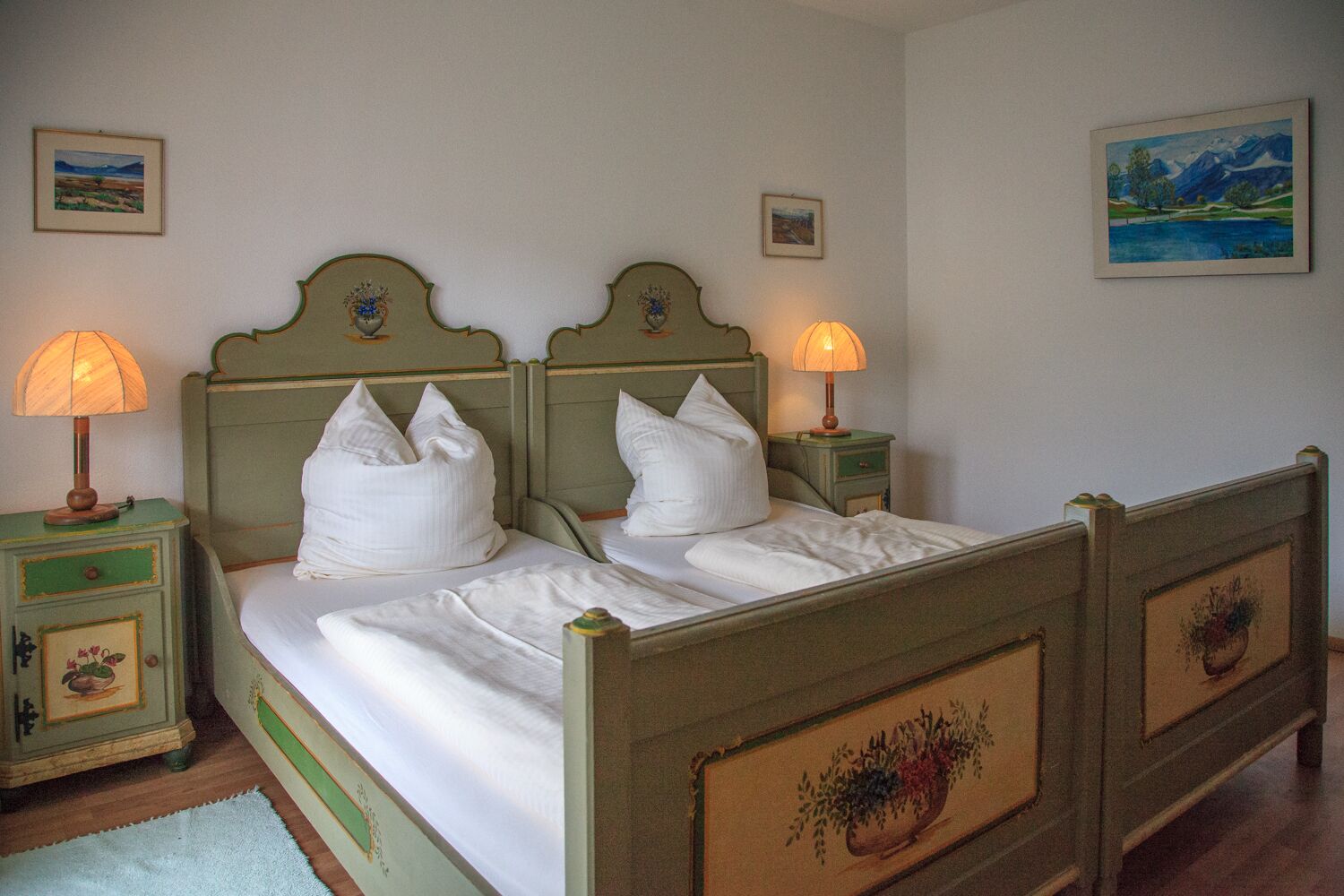 A double bed with two nightstands, each with a lamp, in a room with framed artwork on the walls.