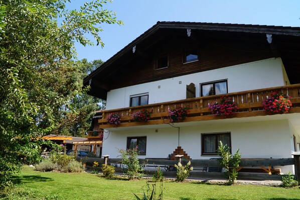 A two-story building with a balcony, a small garden, and a wooden fence.