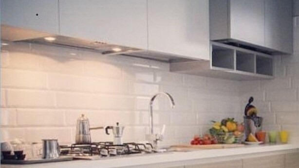 Une cuisine moderne avec un plan de travail blanc, des appareils en acier inoxydable et des armoires en bois.