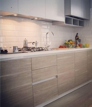 A modern kitchen with a white countertop, stainless steel appliances, and wooden cabinets. - Da Vinci (Matera)
