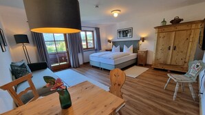 Ein Schlafzimmer mit einem Bett, einem Holztisch, einem Stuhl, einem Schrank und einem Fenster mit Vorhängen.