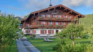 Ein traditionelles Holzhaus mit Balkonen und einem Steinfundament, mit einem Schild, auf dem 'Menzenhof' steht.