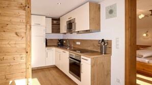 A modern kitchen with wooden cabinets, a built-in oven, and a microwave. - Ferienwohnung Panoramablick 2 - 5 Personen (Berchtesgaden)