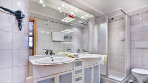 Une salle de bain avec deux lavabos, une douche et des toilettes.