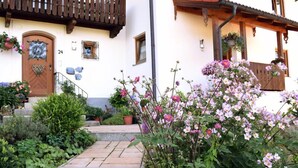 A building with a wooden balcony, a stone staircase, and a variety of flowers.