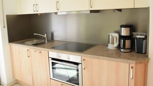 A compact kitchen with a stainless steel sink, a built-in oven, and a coffee maker.