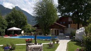 A pool area with a stone pathway leading to a wooden cabin. - 5. Fewo Kampenwand, 28 qm, 1-2 Pers., Wohn-Schlafraum, Westbalkon 2. OG (Grassau)