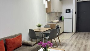 A modern kitchen with a dining area, a sofa, and a coffee table with a vase of flowers. - Corvin Rose Apartment Hotel (Budapest)