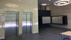 A lobby with two elevators, a reception desk, and a wall-mounted keycard storage. - Corvin Rose Apartment Hotel (Budapest)