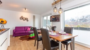 Un comedor moderno con una mesa de madera, sillas negras y un sofá morado.