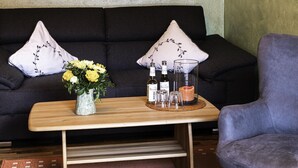 A living room with a sofa, a coffee table with a vase of flowers, and a chair.