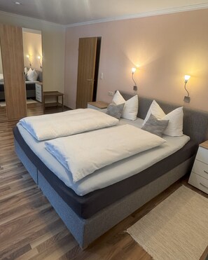 A double bed with a grey headboard, two bedside tables, and a nightstand. - Ferienwohnung Edelweiß, 2 Personen, 57 m², Dusche/WC, TV,1 Schlafzimmer,Terrasse,Internet,Infrarot-Wärmekabine,Nichtrauc (Ramsau bei Berchtesgaden)