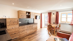 Una cocina moderna con armarios de madera, un lavamanos integrado y una zona de comedor con mesa y sillas.
