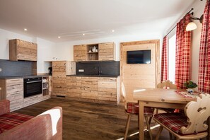 A compact kitchen with wooden cabinets, a built-in oven, and a dining area with a table and chairs.