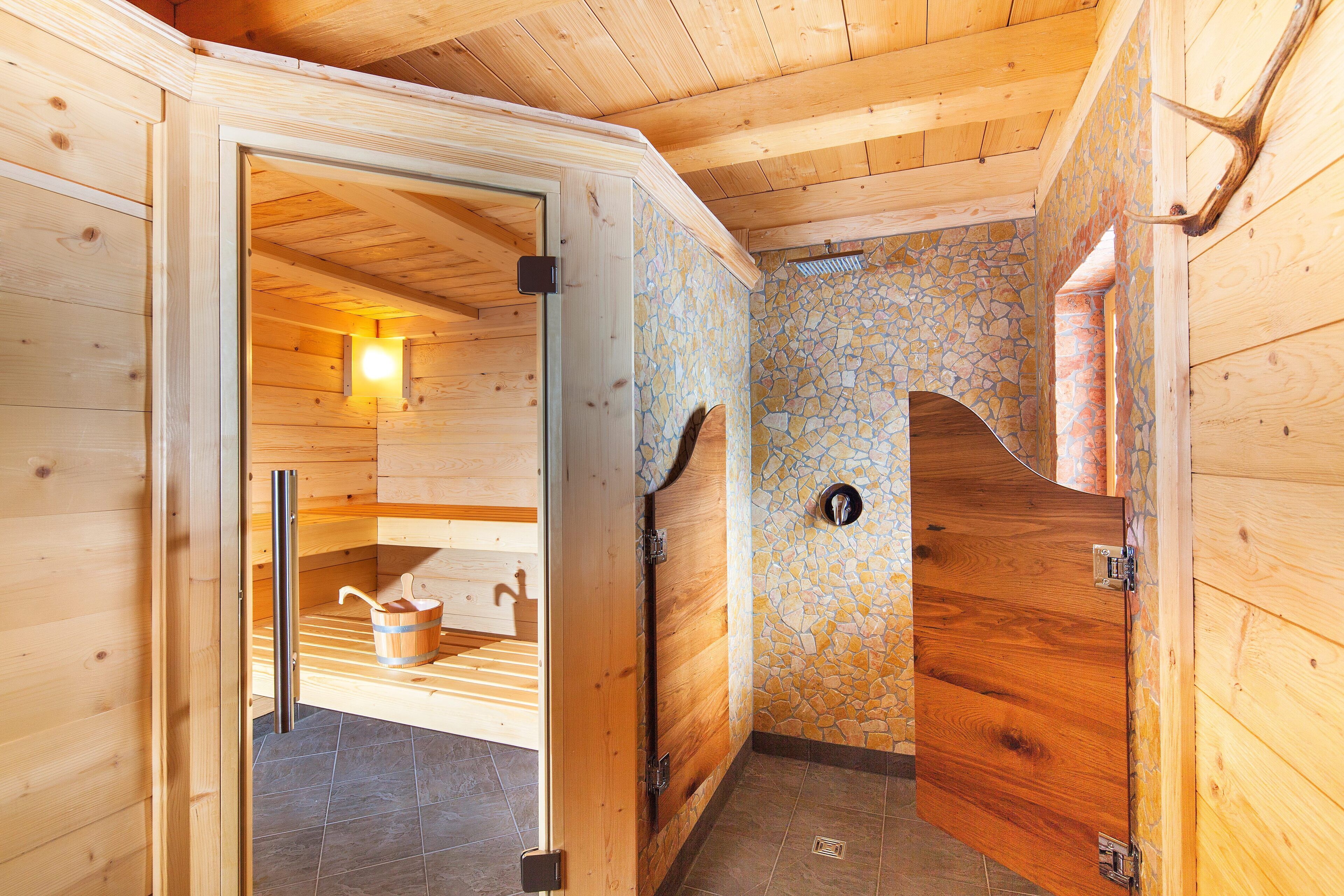 Un sauna en bois avec un mur en pierre, une porte en bois et un porte-serviettes.