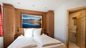 Un dormitorio con una cama de madera, un cuadro grande de un paisaje montañoso y paredes de madera.