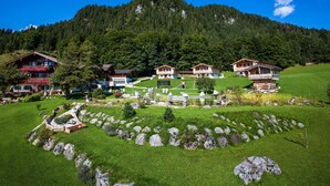 Un complejo turístico de montaña con edificios de estilo chalete, un césped cuidado y un paisaje rocoso.