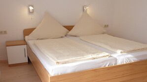 Quarto individual com uma cama de solteiro, cabeceira de madeira, duas mesas de cabeceira e um pequeno armário.