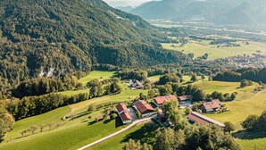 En landlig landsby med huse på en skråning, omgivet af skovdækkede bjerge.