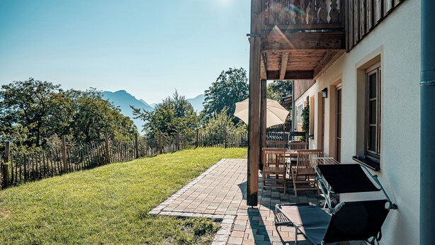 En terrasse med udendørs møbler, en træpergola og udsigt til bjerge.