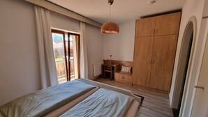 Een slaapkamer met twee bedden, een houten garderobe, een radiator en een raam met gordijnen.