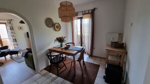 Een eetgedeelte met een houten tafel, stoelen, een vaas met bloemen en een hanglamp.