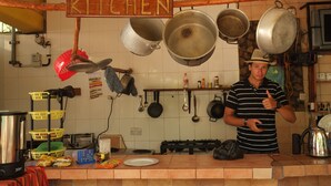 A kitchen with hanging pots, a stove, and a sign that reads "JIKONI KITCHEN". - Homeland Swahili Lodge - Hostel (Nungwi)