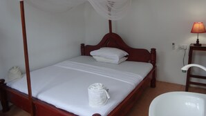 A single bed with a wooden frame and a canopy, a bedside table with a lamp, and a white sink. - Homeland Swahili Lodge - Hostel (Nungwi)
