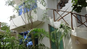 A multi-story building with balconies, a staircase, and surrounding greenery. - Homeland Swahili Lodge - Hostel (Nungwi)