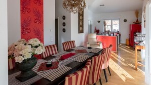 A dining area with a long table, striped chairs, and a vase of white flowers. - Deluxe loft 150 sqm with 2 bedrooms for 1-6 persons and balcony (Bad Reichenhall)